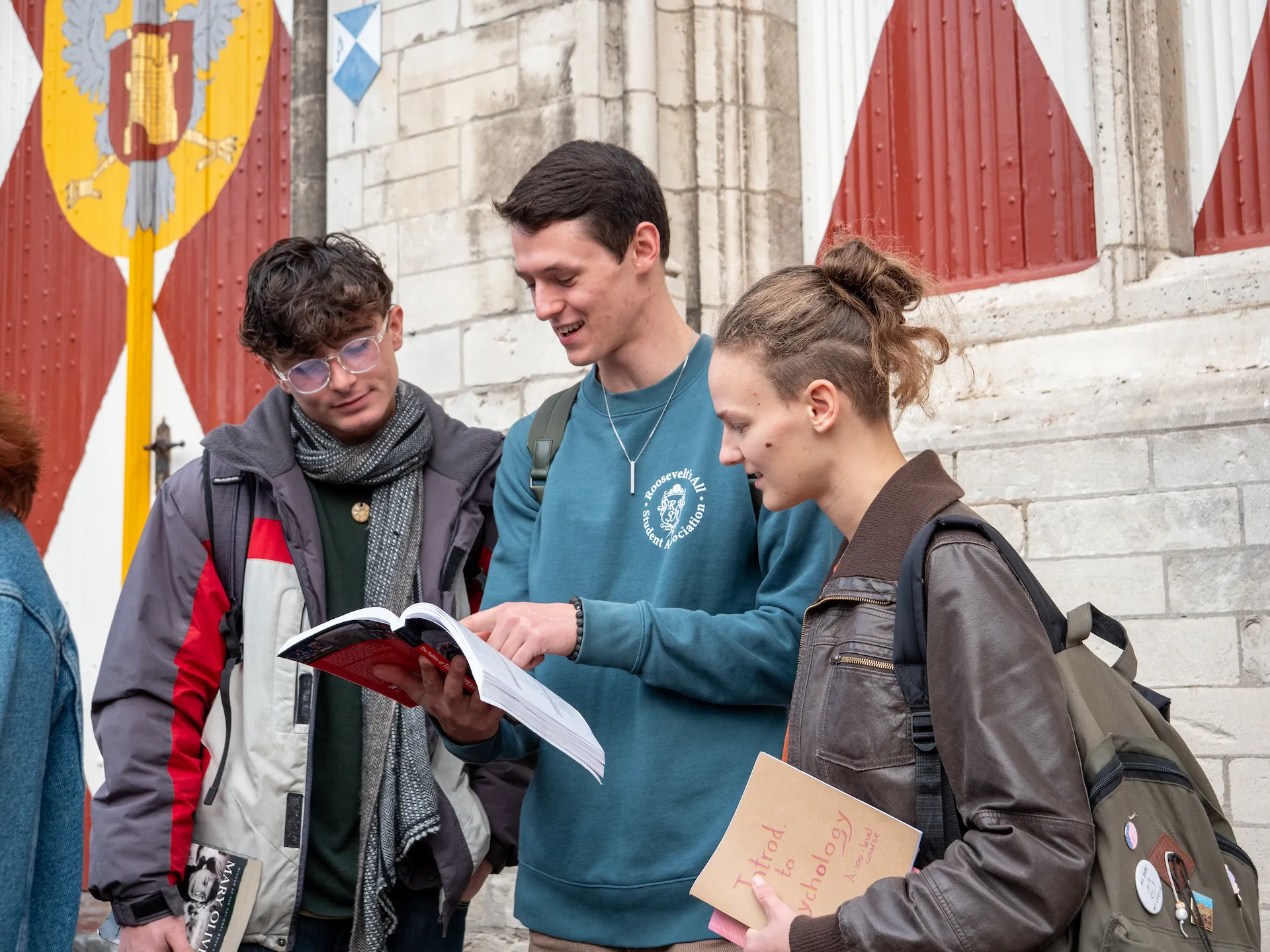 Three college students looking at a book