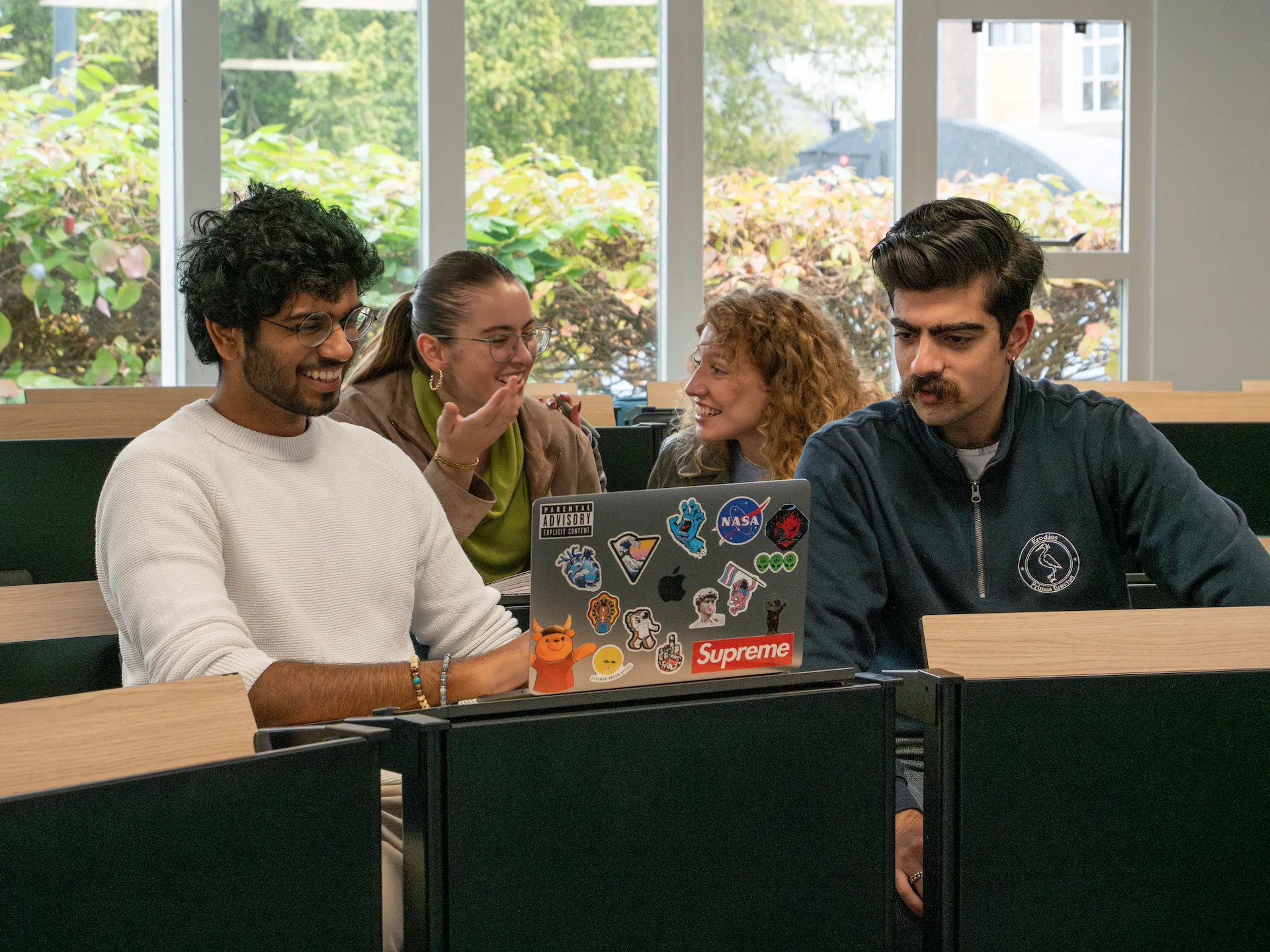 College Students sitting in class with their laptops working and laughing