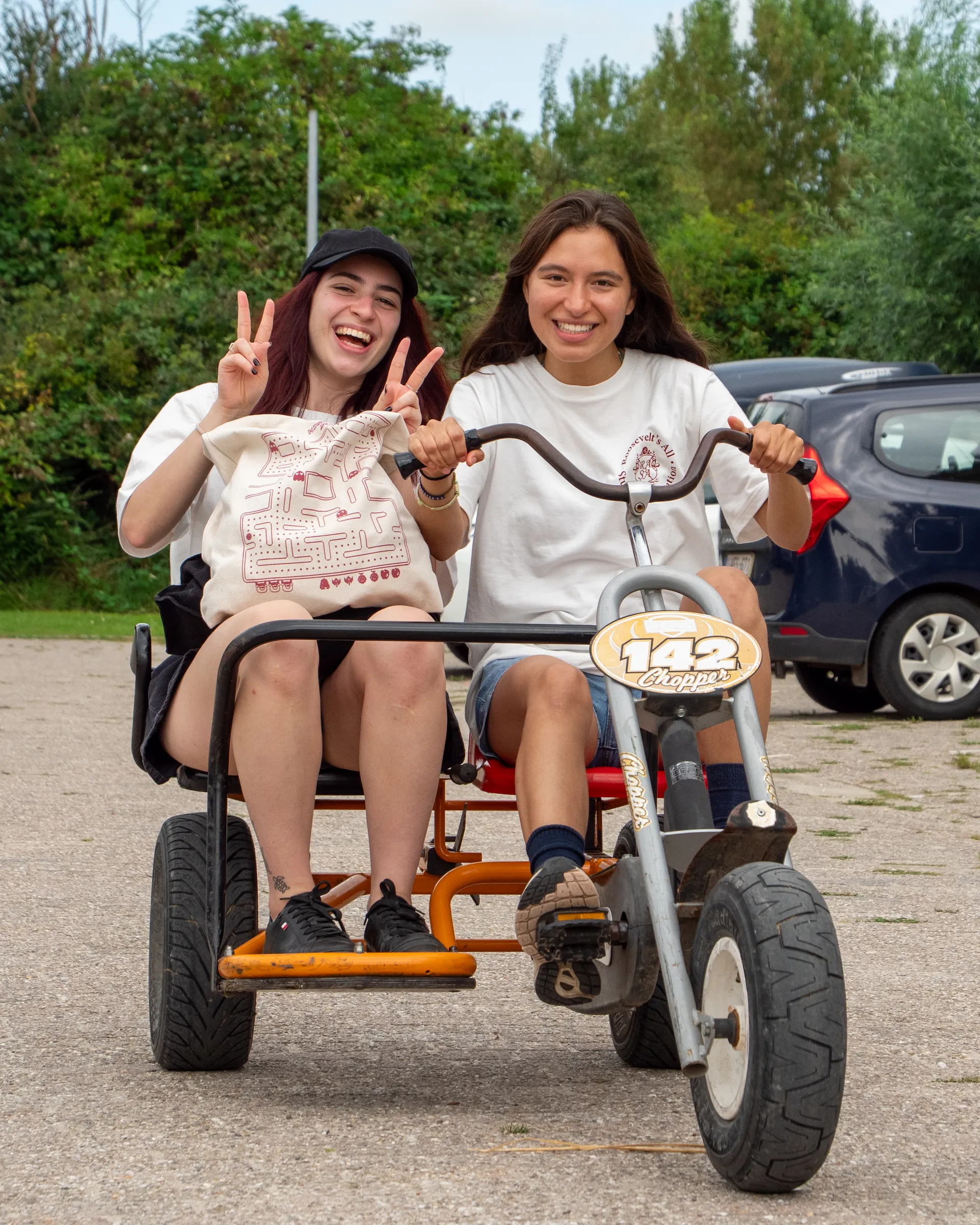 Two college students smiling on a seated bike peddling
